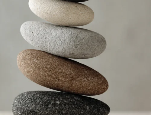 Smooth natural stones carefully stacked in balance against a soft neutral background, symbolising calm, stability, and emotional balance.